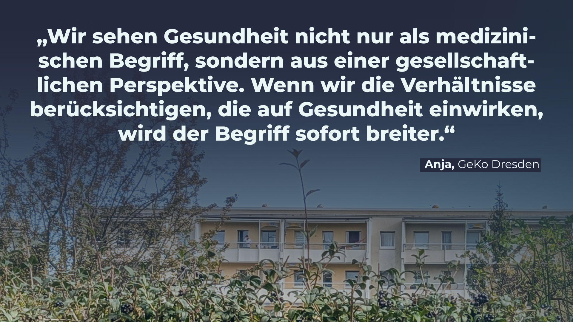 Foto eines Plattenbaus hinter einer Hecke. Über das Bild ist ein dunkelblauer Schatten gelegt. Darauf steht: “Wir sehen Gesundheit nicht nur als medizinischen Begriff, sondern aus einer gesellschaftlichen Perspektive. Wenn wir die Verhältnisse berücksichtigen, die auf Gesundheit einwirken, wird der Begriff sofort breiter.” Anja, Geko Dresden.