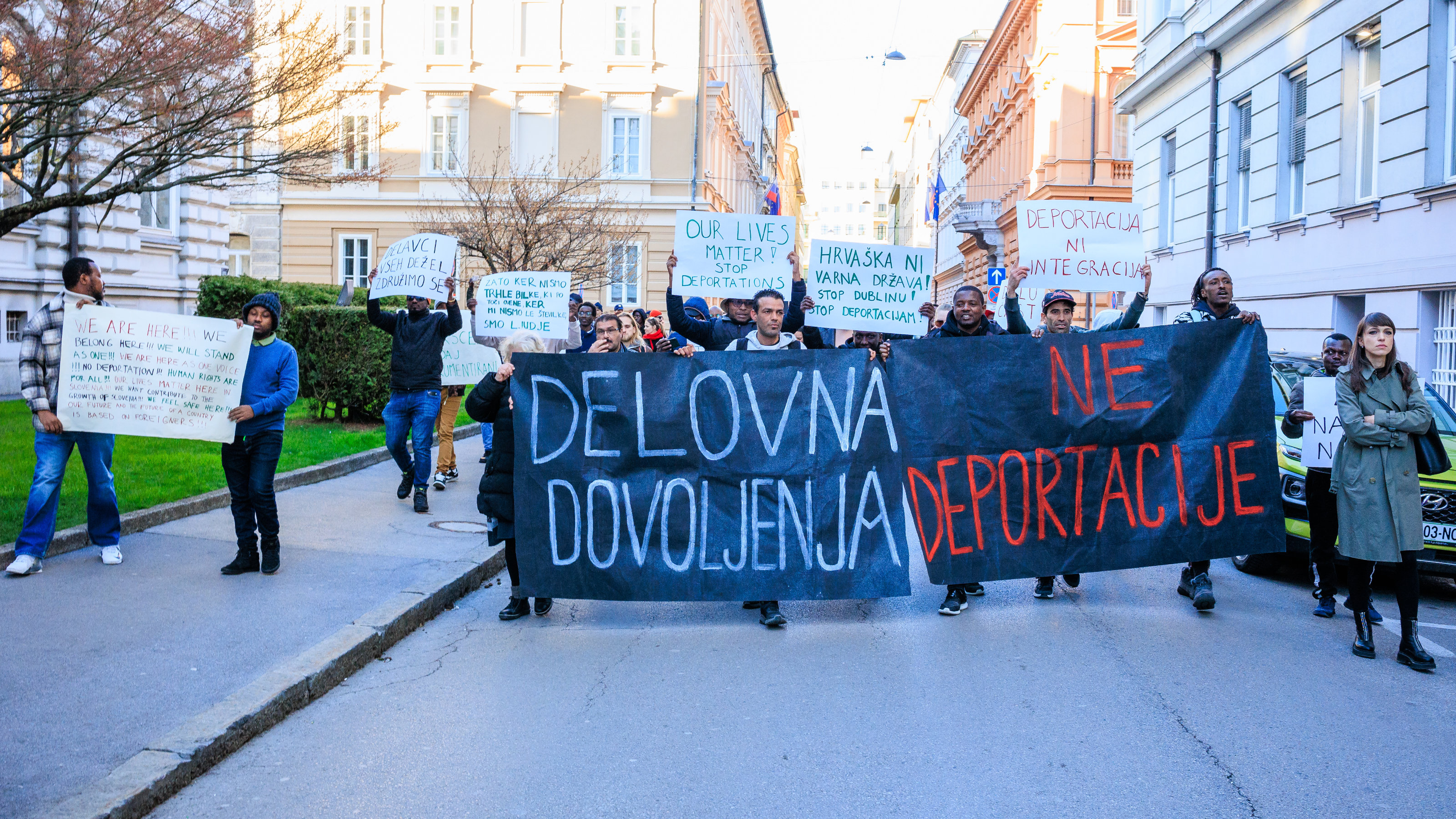 Demonstrationszog der Aktivist*innen von Ambasada Rog in Ljubljana, Slowenien. Auf dem Transparent steht auf slowenisch: Arbeitserlaubnisse – keine Abschiebungen